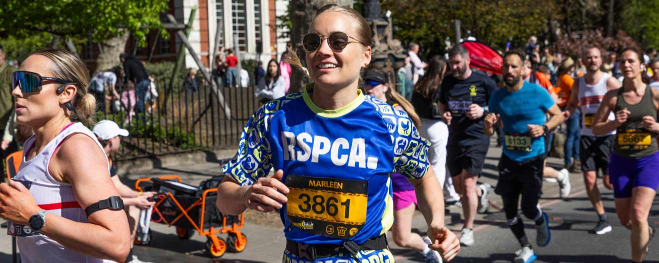 A female fundraiser running for the RSPCA in an organised road marathon event.