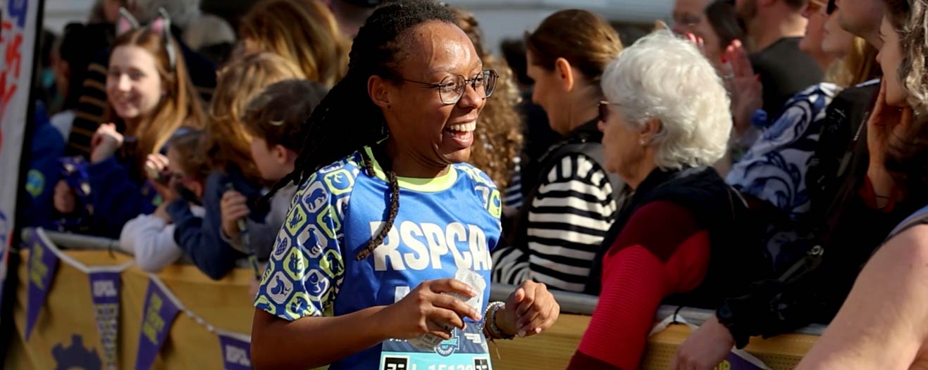 An RSPCA charity runner running past crowds of supporters.