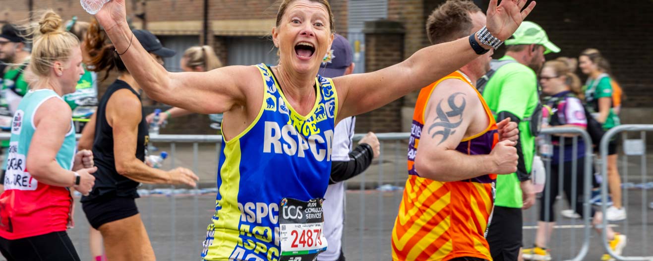 An RSPCA fundraiser running and waving while wearing their RSPCA running vest.