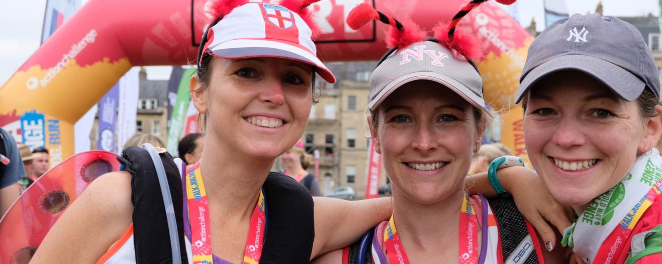 Three happy looking fundraisers at the end of their charity run smiling into camera.
