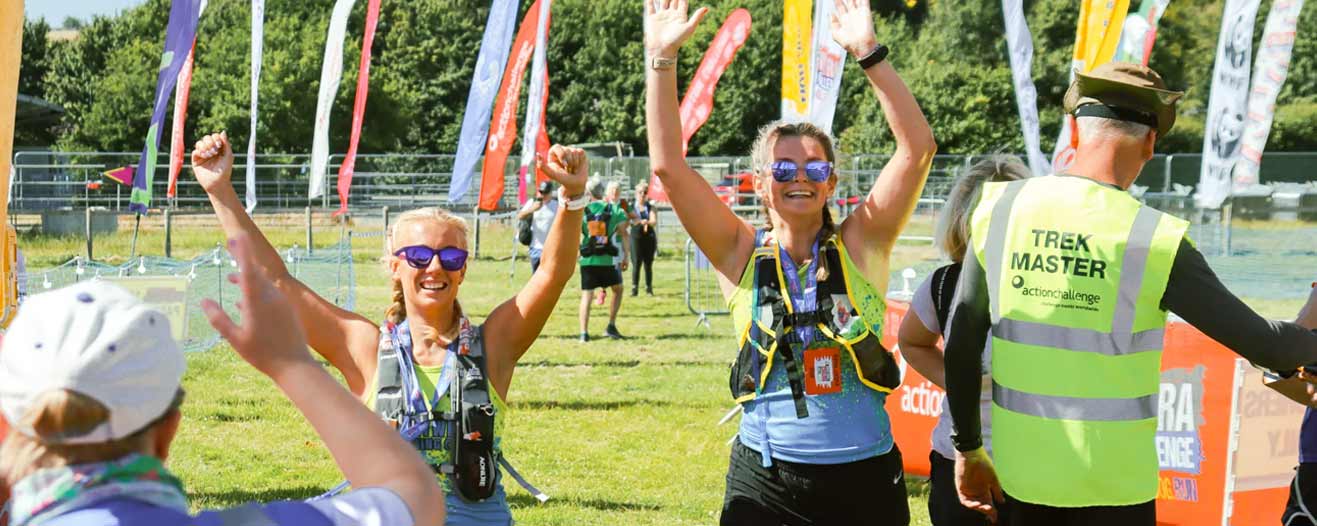 Two jubilant Peak District Challenge finishers with their hands in the air.