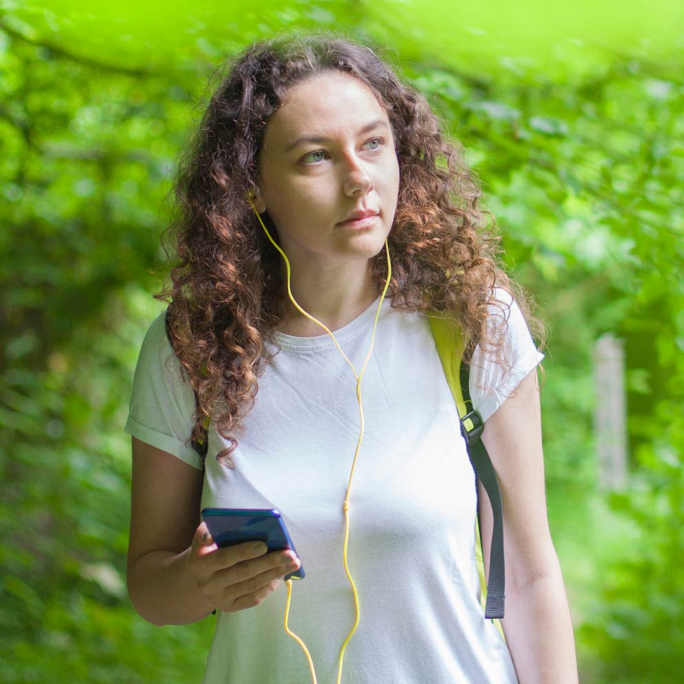 Young woman listening with headphones while walking outside.