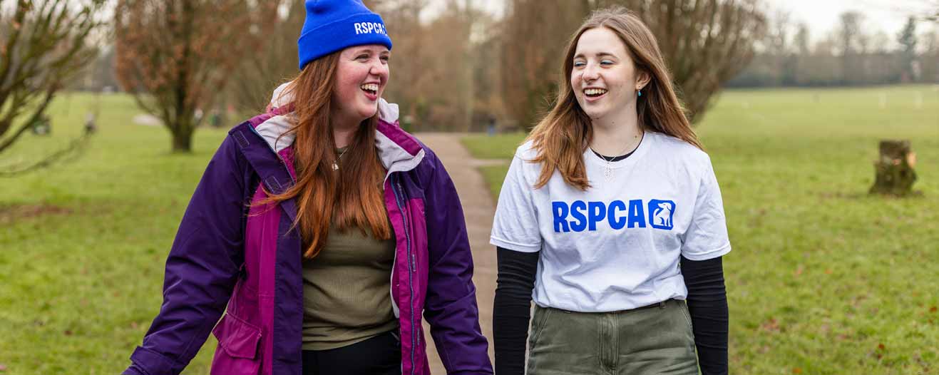 Two women walking along a footpath in a park.