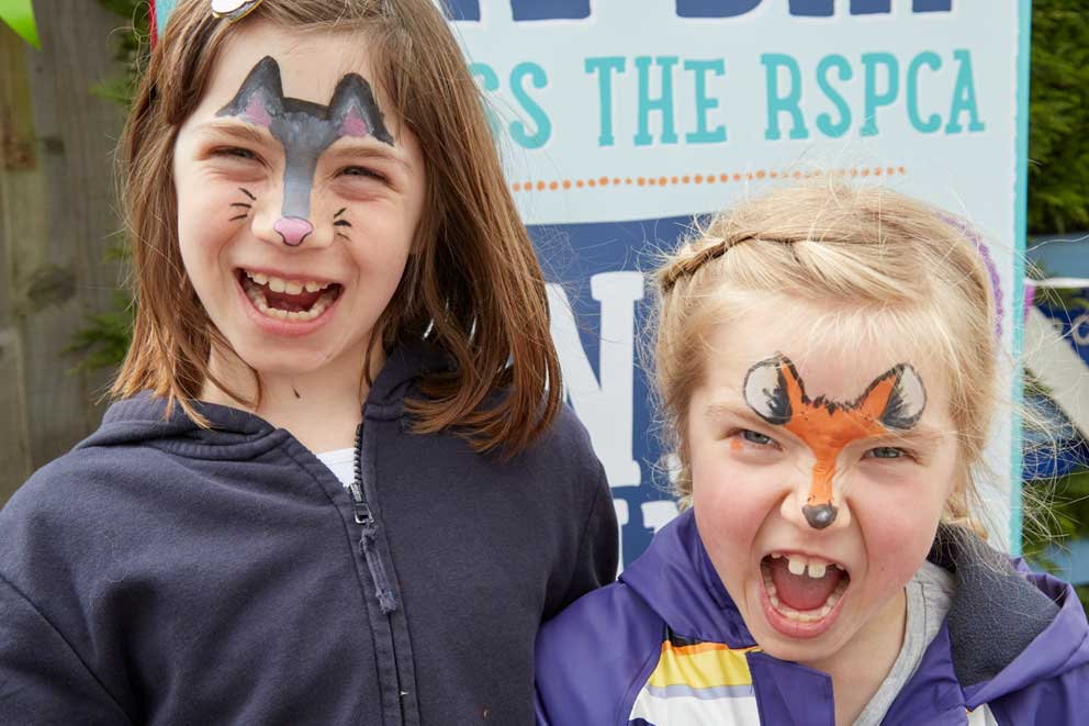 Two young fundraisers with animal face paint at a fundraising event.