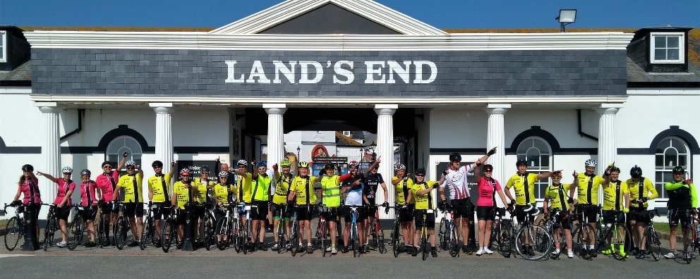 Cyclists cheering at Lands End in Cornwall