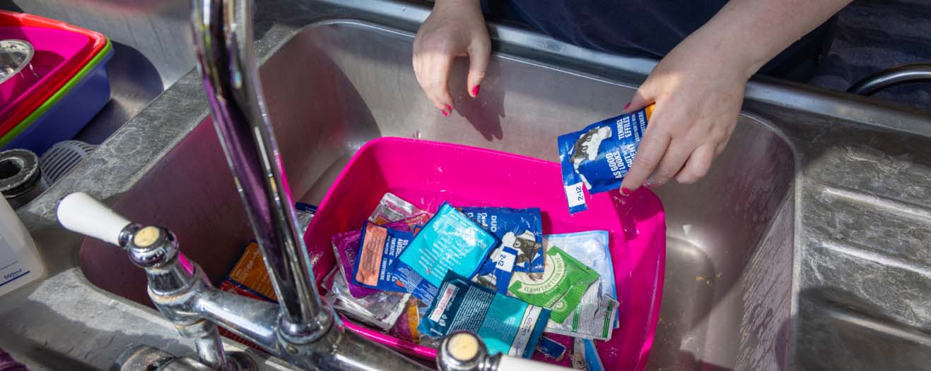 Cat food pouches being washed out in a sink.