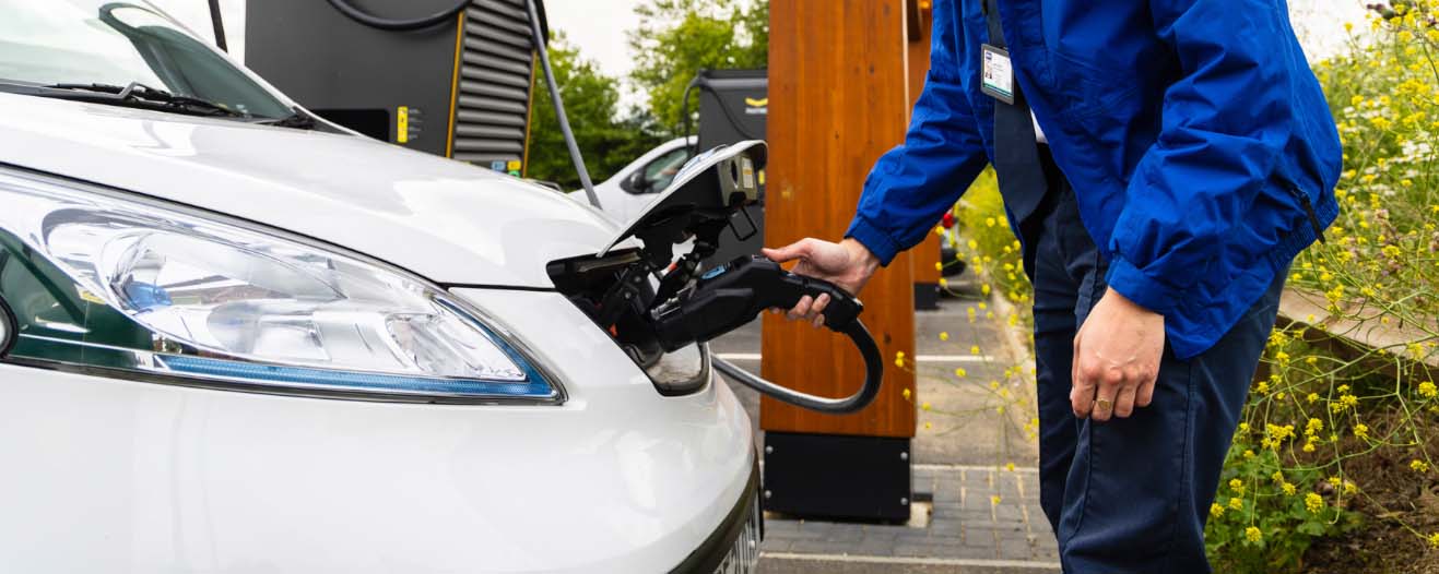 An RSPCA staff member plugging in a car to a charging point.