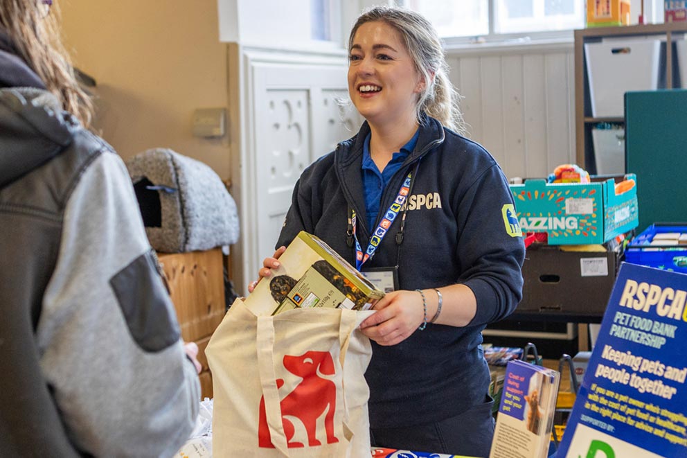 RSPCA staff member handing a pet food bank package to a member of the public.