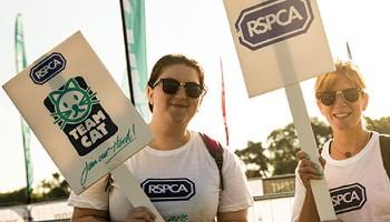 Two RSPCA volunteers holding plaques for fundraising