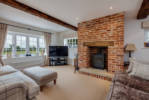 A living room with exposed wooden beams, brick fireplace, and modern amenities.