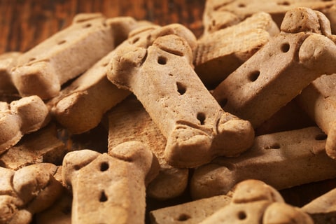 Close up of assorted dog treats stacked on a wooden table.