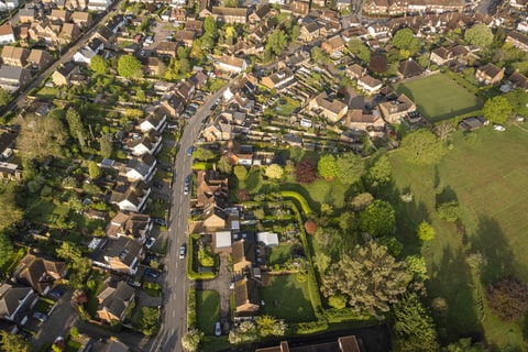 Aerial view of houses and trees with a road running through the middle. 