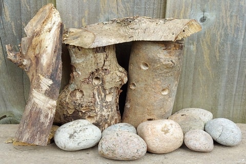 A selection of small logs and rocks next to a garden fence. 