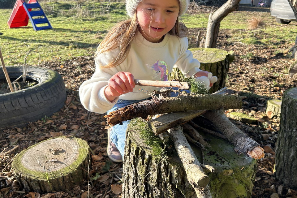 A young person building a bug home with sticks