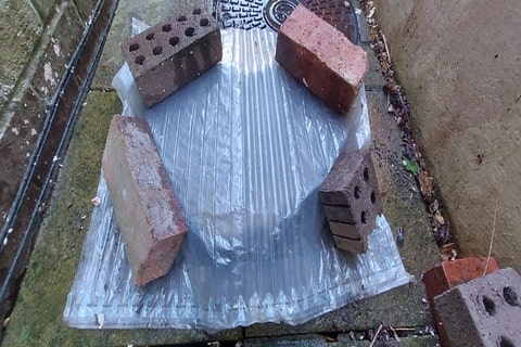 Covering the disinfectant with plastic sheeting and bricks to prevent any animals from being harmed.