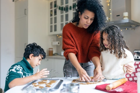 A parent and her children baking in a kitchen.