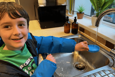 A young child filling up a cup of water.