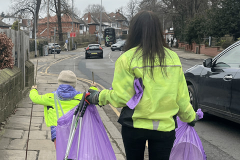 An adult and a child with litter bags after a litter pick.