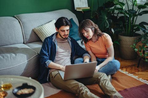 Young couple sitting on the floor researching pet advice online