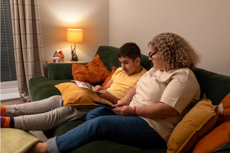 A young boy and his mother talking on a couch