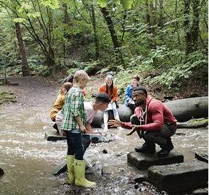 A group of children exploring a forest and a stream