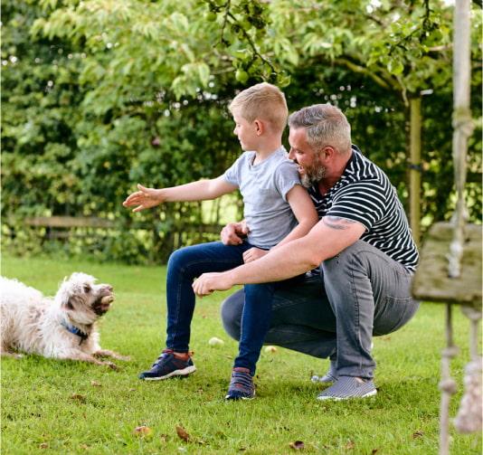 A young boy and his father playing with a dog