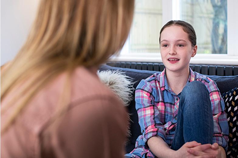 A young girl talking to a parent on a couch