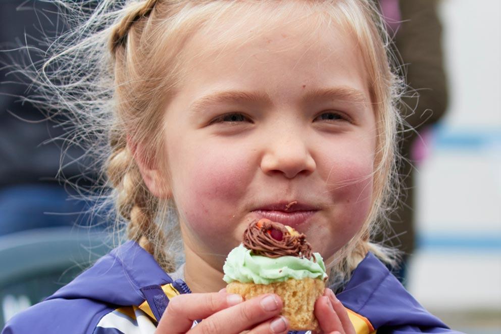 Young girl smiling and eating a cupcake.