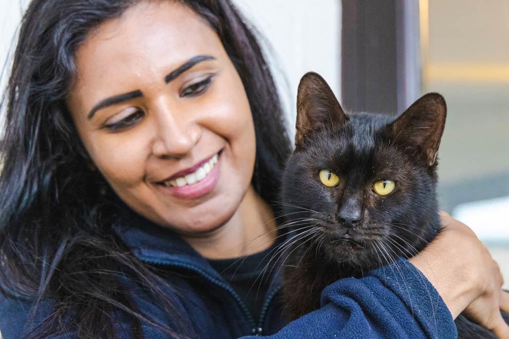 Smiling woman holding a black cat.