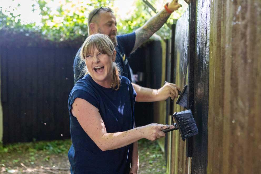 Corporate volunteers staining an outside fence.