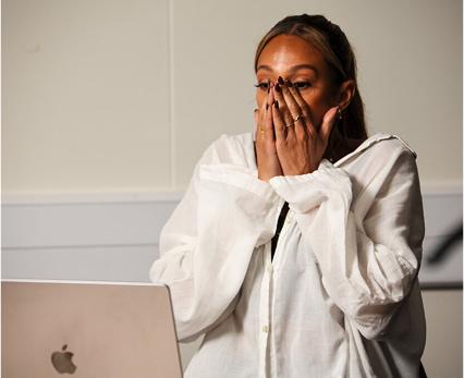 Alesha Dixon watching footage on an open laptop, her hands over her face in shock.