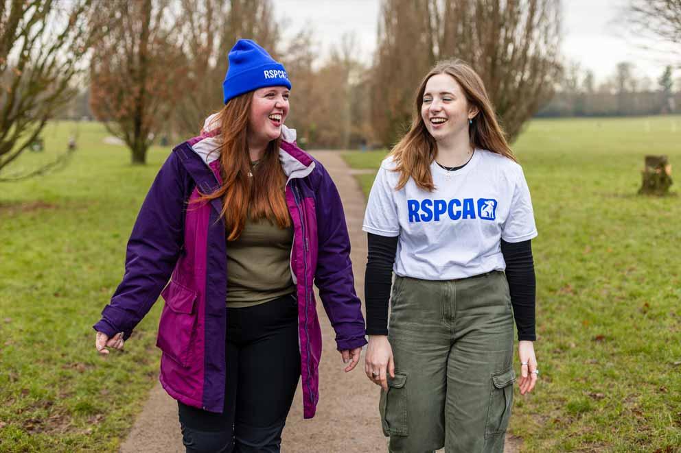 Two young women walking outdoors wearing RSPCA branded merchandise.