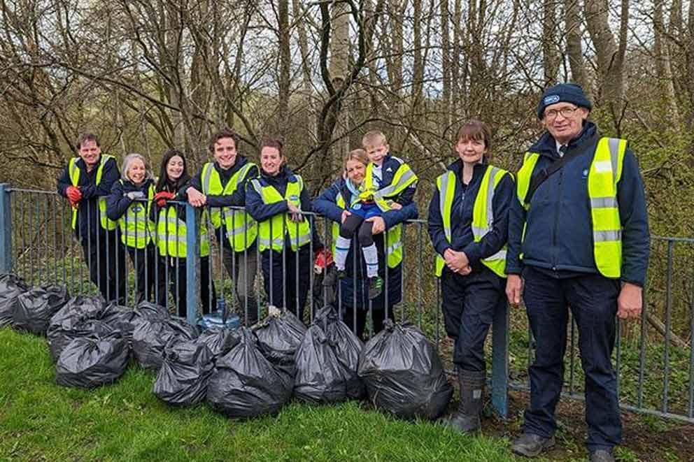 A group of community volunteers standing with bags of rubbish collected outside.