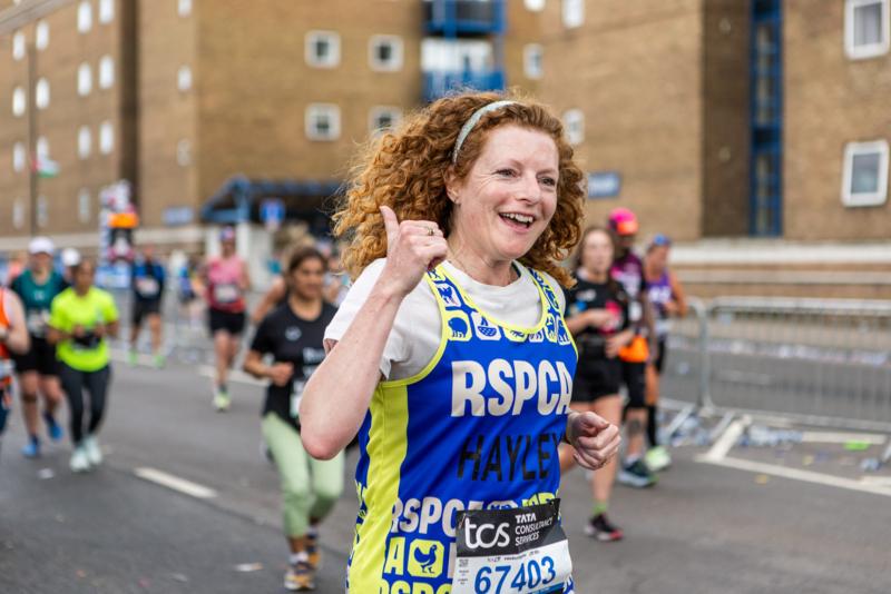 A runner giving the thumbs up as racing past crowds.