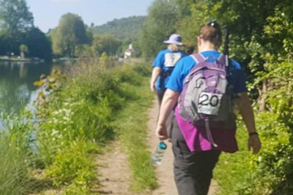 Two walkers wearing rucksacks walking along side the Thames public footpath.