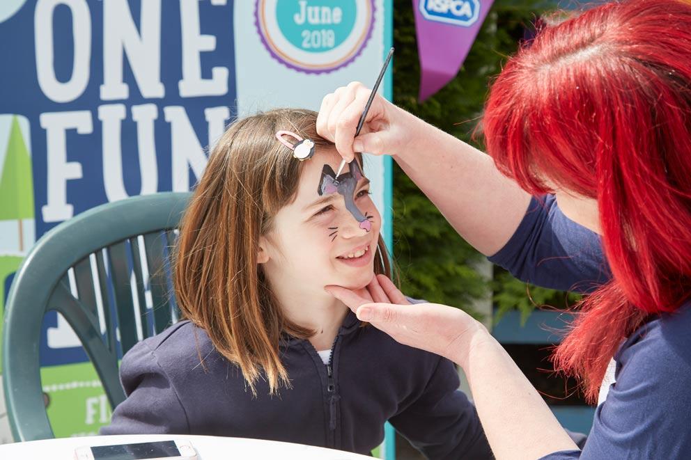 Young girl sitting having her face painted.